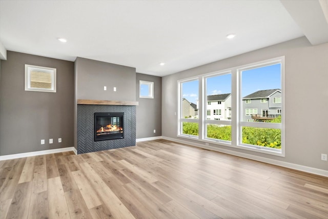 unfurnished living room featuring light wood-style flooring, baseboards, and a tile fireplace