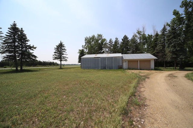 view of yard featuring a garage, an outbuilding, an outdoor structure, and driveway