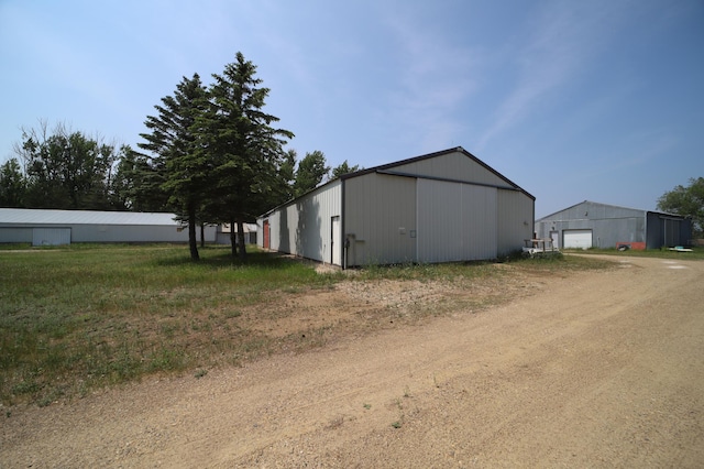 exterior space featuring driveway, a detached garage, a pole building, and an outdoor structure