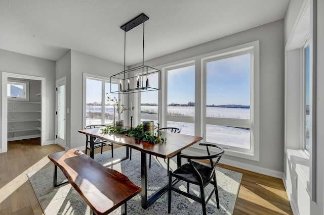 dining area with a chandelier, light wood-style flooring, and baseboards