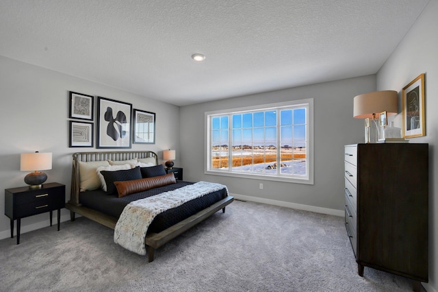 bedroom featuring light colored carpet, a textured ceiling, and baseboards