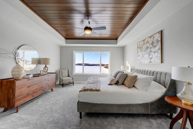 bedroom featuring wooden ceiling, multiple windows, a raised ceiling, and carpet flooring