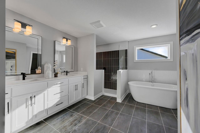 bathroom with double vanity, a freestanding bath, a sink, tile patterned flooring, and walk in shower