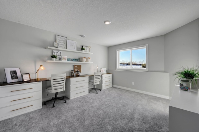 home office with light colored carpet, a textured ceiling, and baseboards