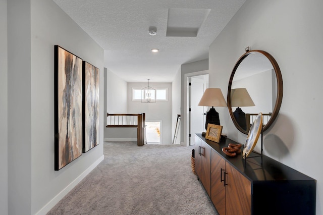 corridor featuring baseboards, light colored carpet, a textured ceiling, and an upstairs landing