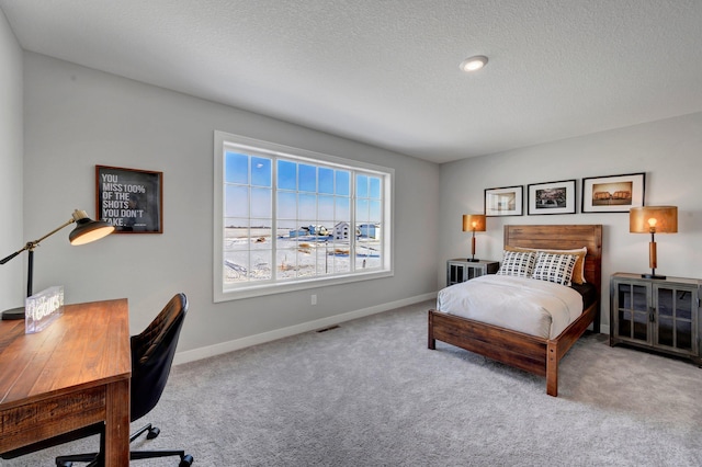 carpeted bedroom featuring a textured ceiling, visible vents, and baseboards