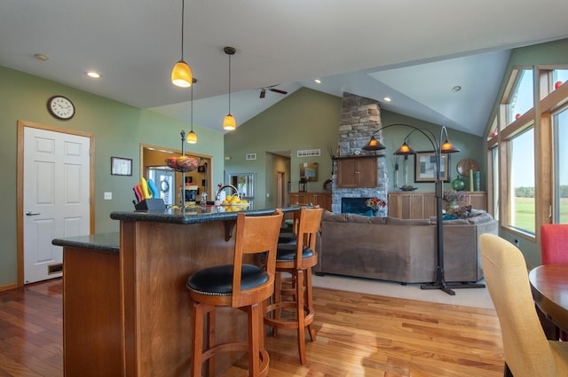 kitchen featuring a kitchen island, open floor plan, a kitchen breakfast bar, light wood-type flooring, and a fireplace