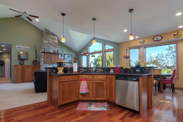 kitchen featuring a sink, visible vents, stainless steel dishwasher, brown cabinetry, and dark countertops