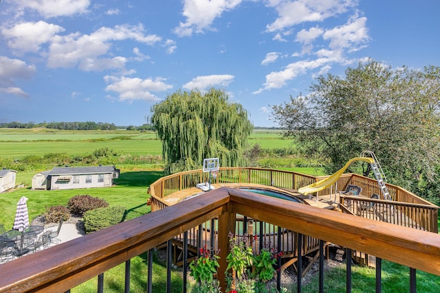 deck featuring an outbuilding, a rural view, a lawn, and a hot tub