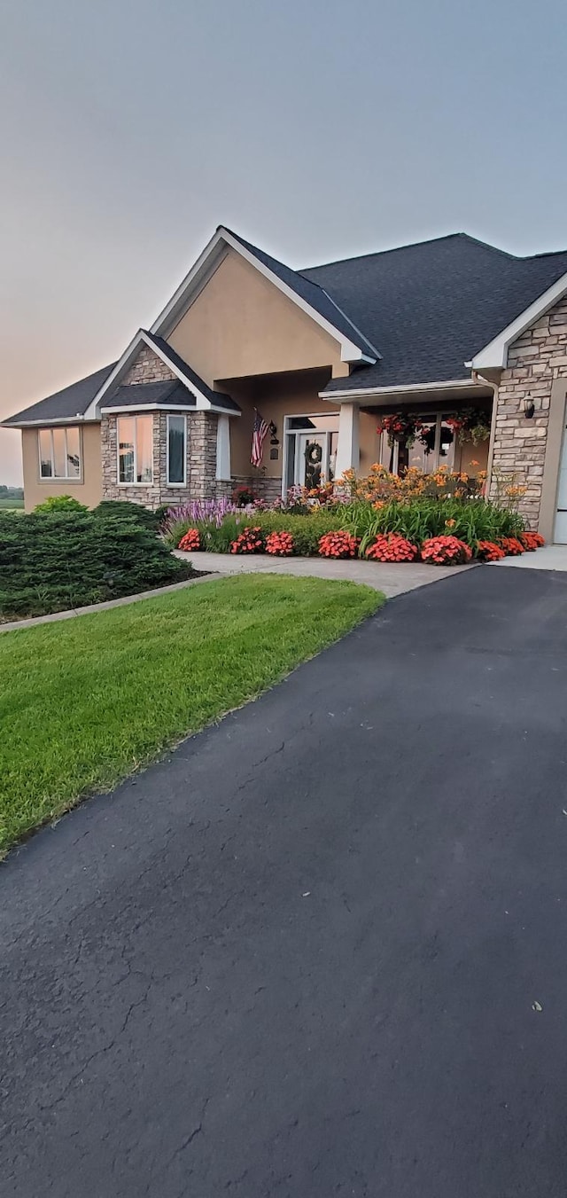 view of front of property with stone siding, a front lawn, and stucco siding