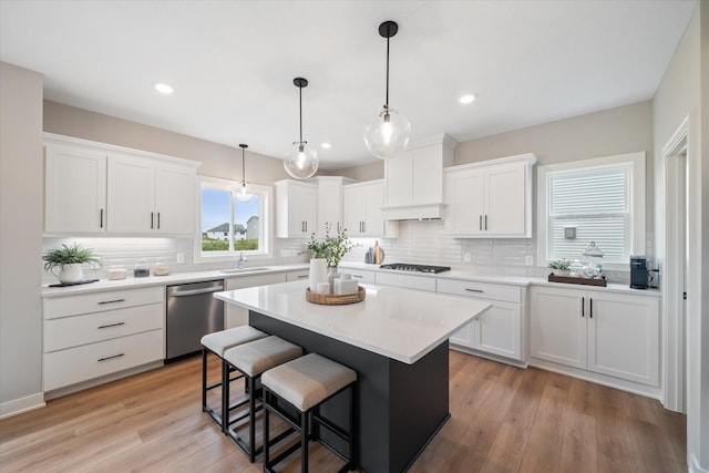 kitchen with gas stovetop, a sink, stainless steel dishwasher, and white cabinetry