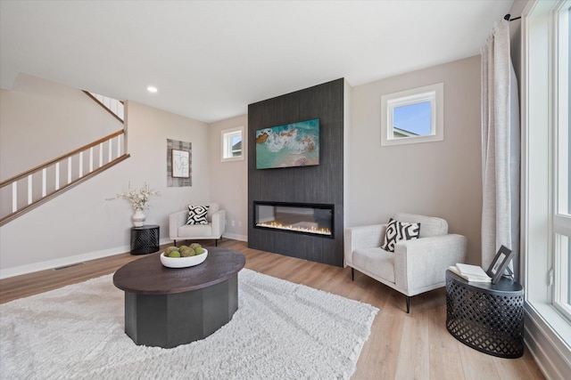 living area with visible vents, a fireplace, stairway, and wood finished floors