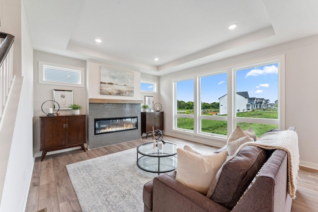 14355 Acer Ave, Rosemount, MN 55068 - living room with a tray ceiling, a tiled fireplace, light wood-style flooring, recessed lighting, and baseboards