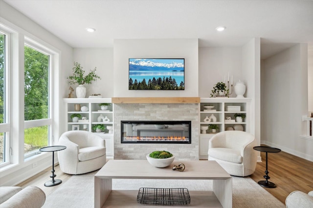 living room featuring recessed lighting, baseboards, wood finished floors, and a glass covered fireplace