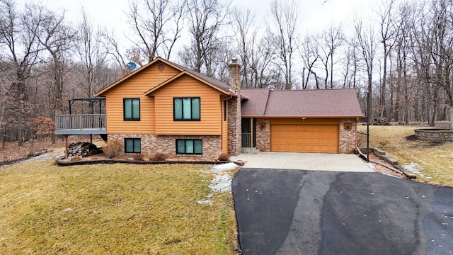 tri-level home featuring driveway, a garage, a chimney, a front lawn, and brick siding