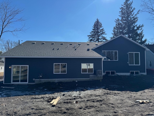 back of house with central AC and a shingled roof