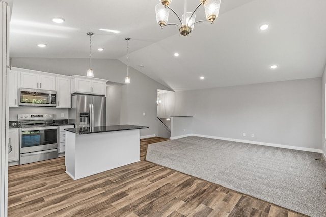 kitchen featuring a notable chandelier, wood finished floors, white cabinetry, appliances with stainless steel finishes, and dark countertops