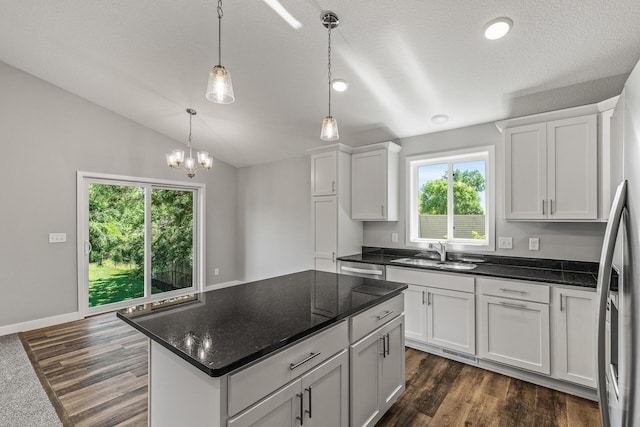 kitchen with vaulted ceiling, dark wood-type flooring, a sink, and white cabinets