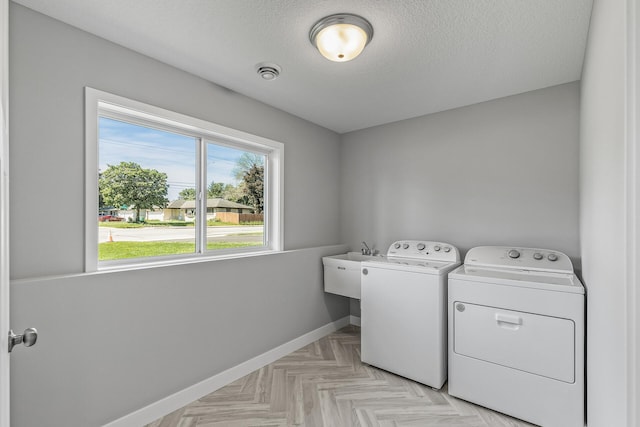 washroom with laundry area, visible vents, baseboards, a textured ceiling, and washing machine and dryer