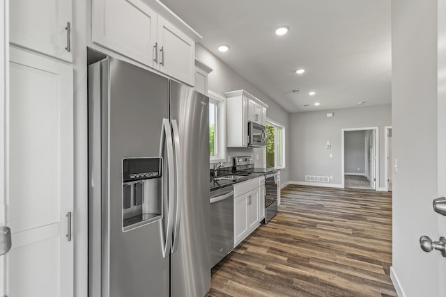 kitchen featuring recessed lighting, stainless steel appliances, dark wood-style flooring, white cabinetry, and dark countertops