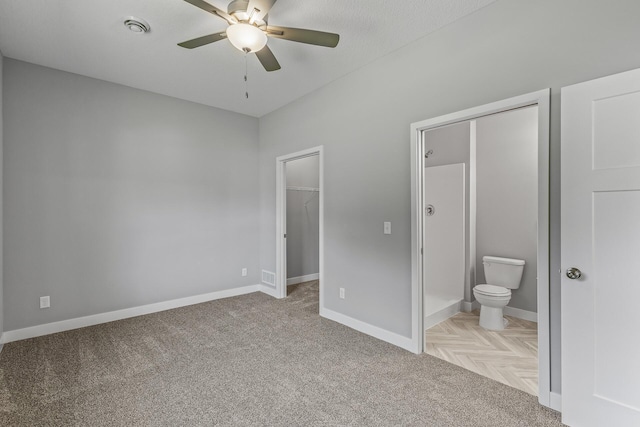 unfurnished bedroom featuring a walk in closet, visible vents, ensuite bathroom, ceiling fan, and baseboards