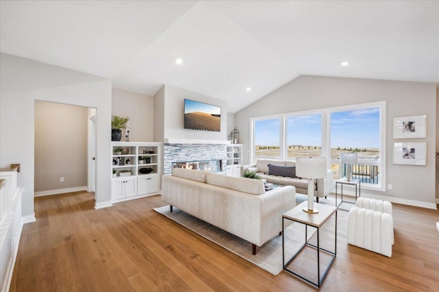 living room featuring light wood finished floors, a fireplace, baseboards, and vaulted ceiling