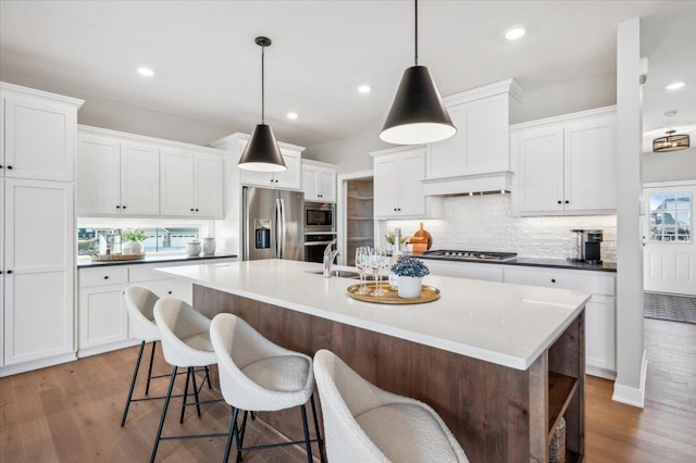 kitchen featuring a sink, appliances with stainless steel finishes, an island with sink, and wood finished floors