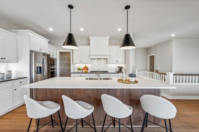 kitchen featuring a sink, tasteful backsplash, stainless steel appliances, and wood finished floors