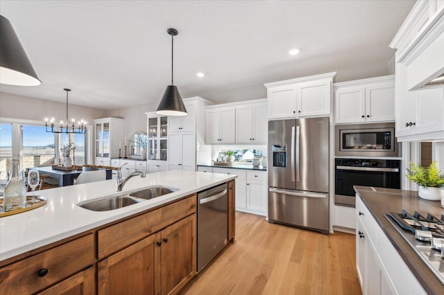 kitchen featuring appliances with stainless steel finishes, pendant lighting, a sink, and light wood-style flooring