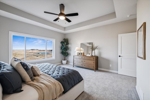 bedroom featuring carpet, a tray ceiling, ceiling fan, and baseboards