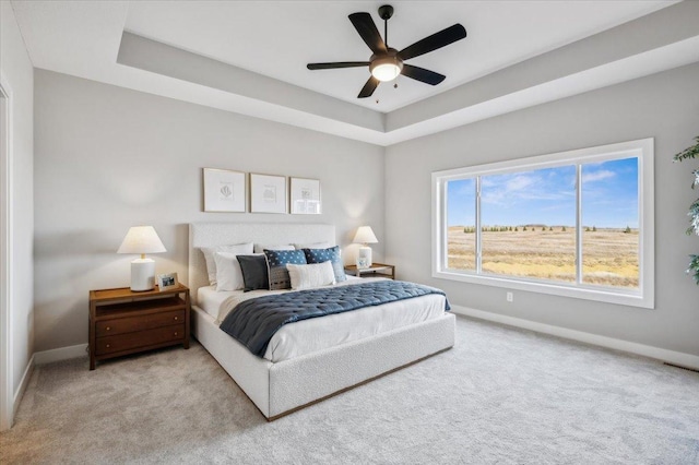 bedroom with carpet, a tray ceiling, and baseboards