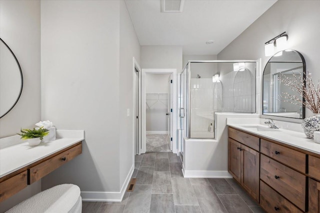 bathroom with vanity, baseboards, visible vents, a walk in closet, and a shower with door