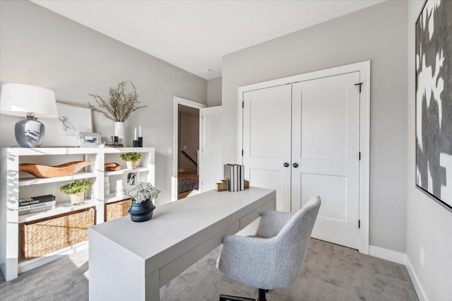 office area featuring light carpet and baseboards