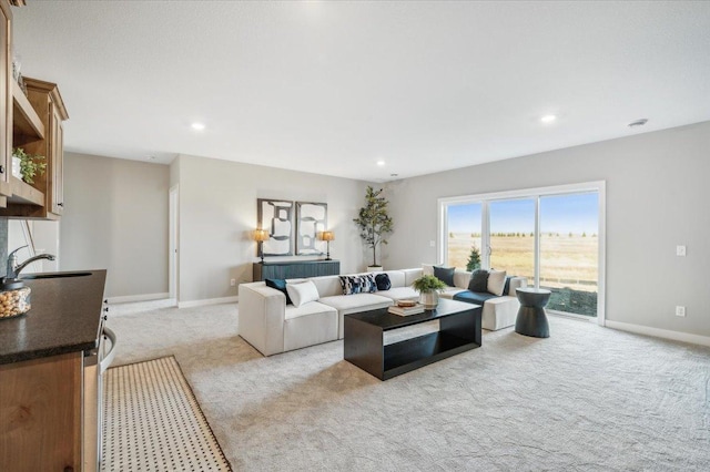 living area featuring recessed lighting, baseboards, and light colored carpet