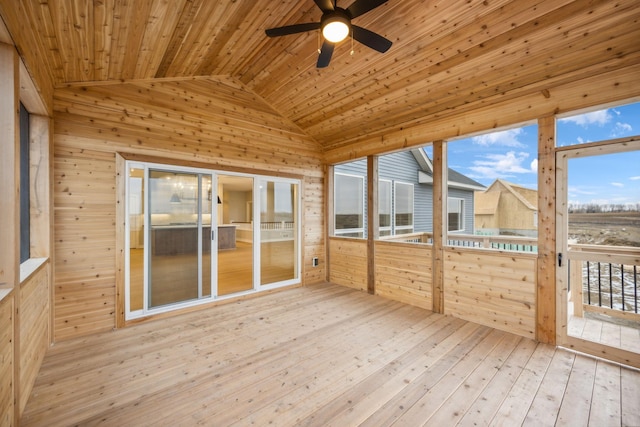 unfurnished sunroom featuring a healthy amount of sunlight, wooden ceiling, vaulted ceiling, and a ceiling fan