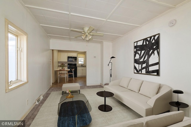 living room with baseboards, visible vents, and ceiling fan