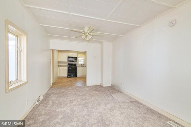 unfurnished room with visible vents, light carpet, a sink, ceiling fan, and baseboards