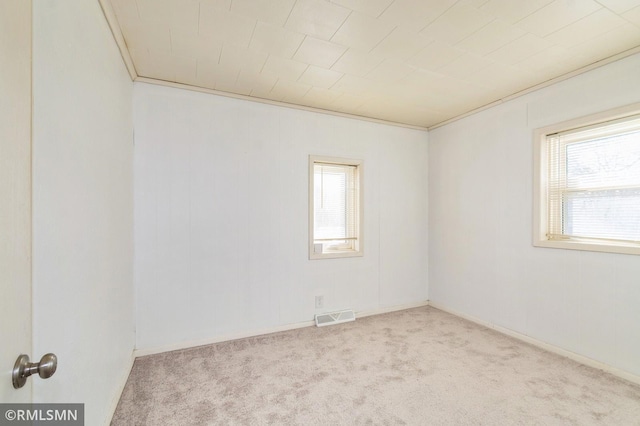 carpeted empty room with ornamental molding, visible vents, and baseboards