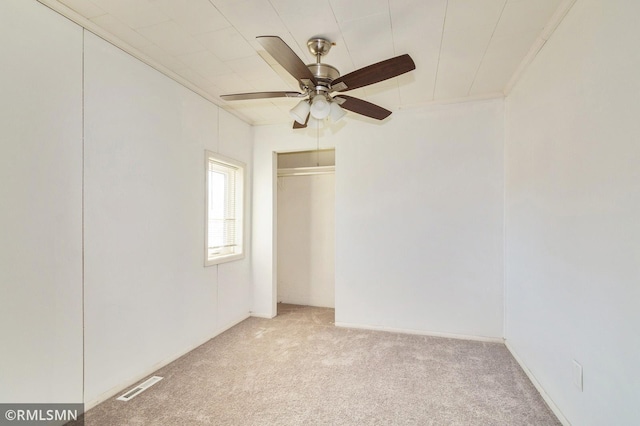 unfurnished bedroom with visible vents, a ceiling fan, light colored carpet, crown molding, and a closet