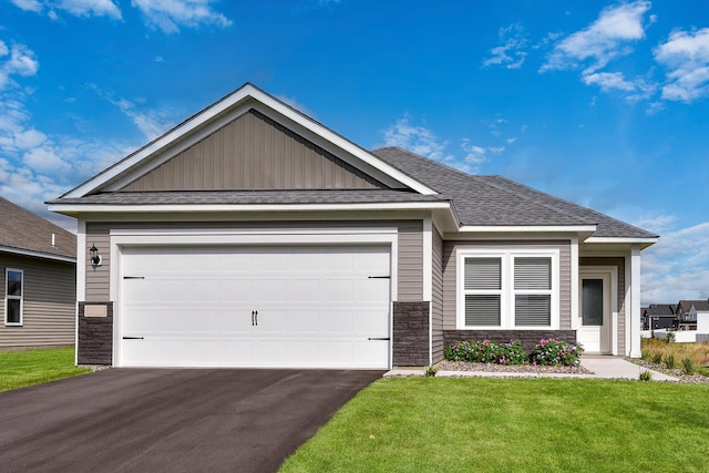 view of front facade featuring aphalt driveway, stone siding, a shingled roof, an attached garage, and a front yard