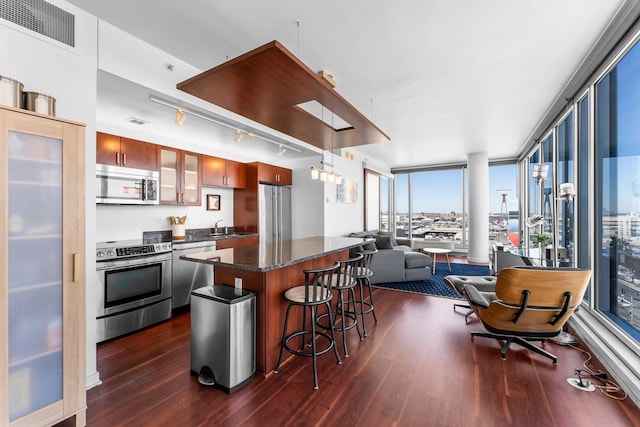 kitchen with visible vents, a sink, open floor plan, appliances with stainless steel finishes, and dark wood-style flooring