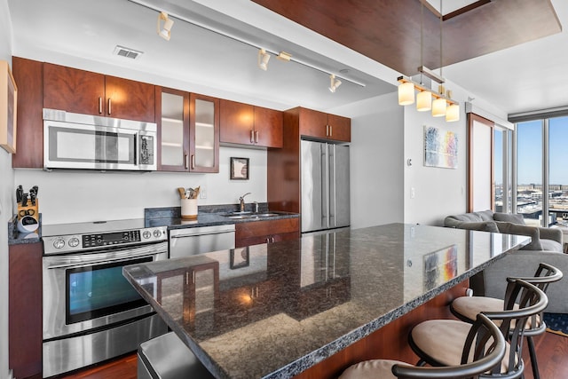 kitchen featuring visible vents, a sink, dark wood-style floors, appliances with stainless steel finishes, and a breakfast bar area