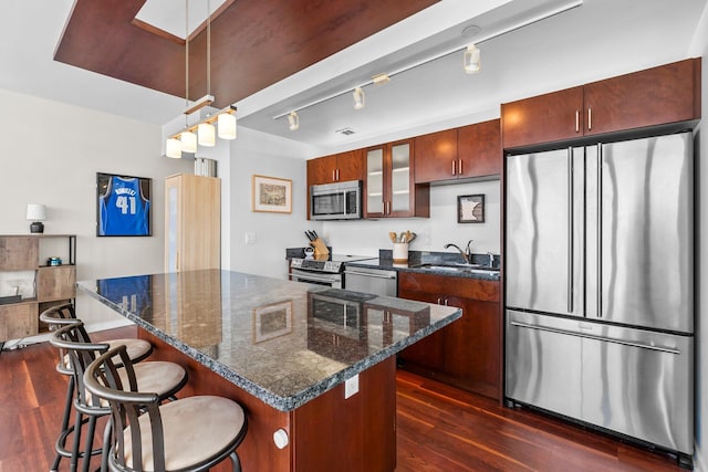 kitchen featuring a kitchen bar, a sink, stainless steel appliances, a skylight, and dark wood-style flooring