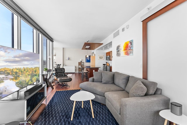 living area with visible vents, expansive windows, rail lighting, and wood finished floors