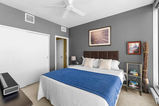 bedroom with light carpet, visible vents, a closet, and a baseboard radiator