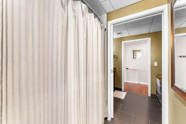 bathroom with tile patterned floors, visible vents, baseboards, and a drop ceiling