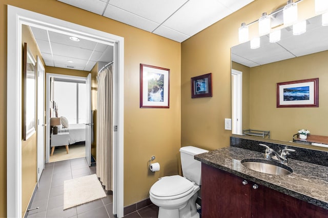 full bath with tile patterned flooring, vanity, toilet, and a paneled ceiling