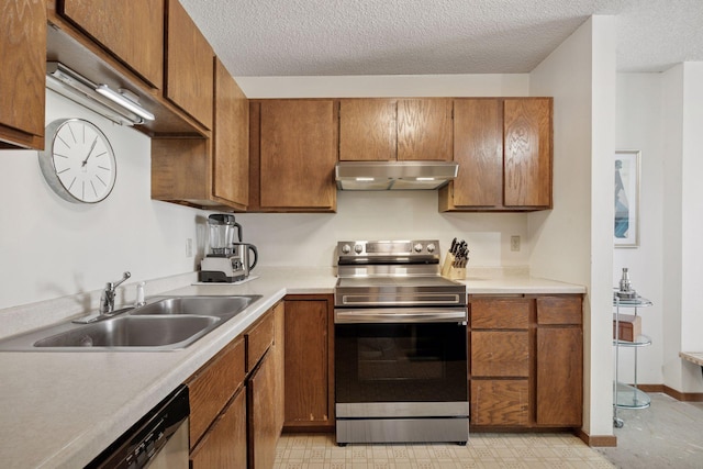 kitchen with stainless steel appliances, brown cabinetry, a sink, and under cabinet range hood