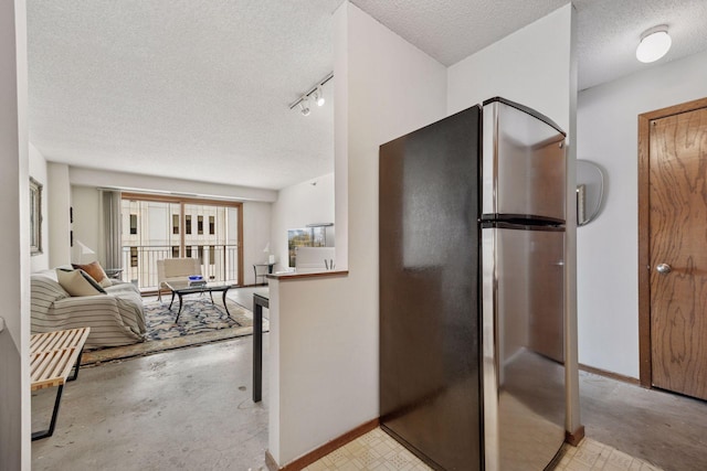 kitchen featuring track lighting, baseboards, a textured ceiling, and freestanding refrigerator