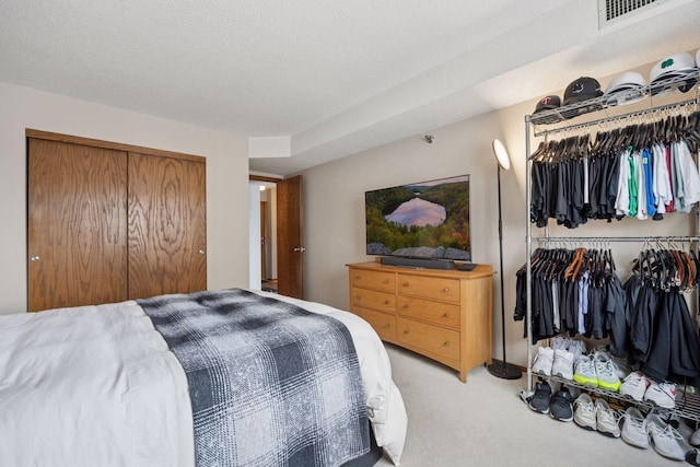 carpeted bedroom with a textured ceiling, visible vents, and a closet